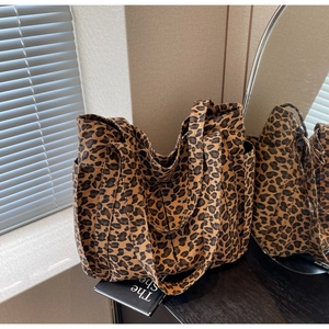 Dettaglio della borsa tote grande in tela leopardata con tasche laterali e manici