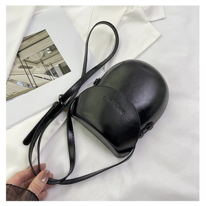 Detail view of the black leather saddle bag featuring an embossed fashion text logo