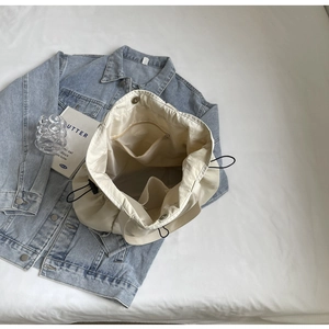 Interior detail of a minimalist tote bag with zipper pocket, snap button and drawstring.