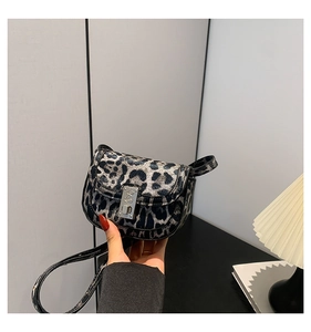 Close-up of leopard print saddle bag featuring a silver rectangular buckle and leather texture