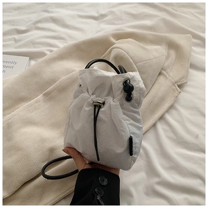 Close-up of white drawstring bucket bag showing pleated nylon fabric and black cord details