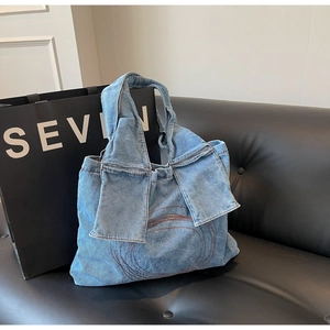 Detail of blue denim tote bag featuring concentric circle stitching and knotted handle