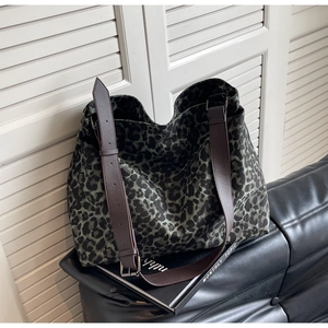Close-up of leopard print canvas tote bag with adjustable brown leather shoulder strap