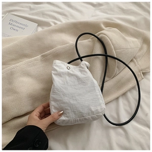 Detail of white nylon drawstring mini bag with black rope strap and silver metal snap button