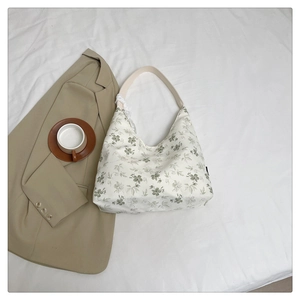 Détail du sac hobo floral avec bandoulière en cuir beige et motif de fleurs sur toile