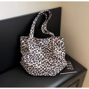 Detail view of leopard print canvas tote bag on a black bench for fashion use