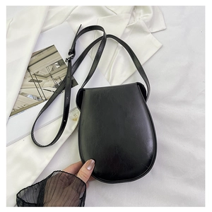Close-up of black minimalist saddle bag in semi-matte leather with adjustable strap