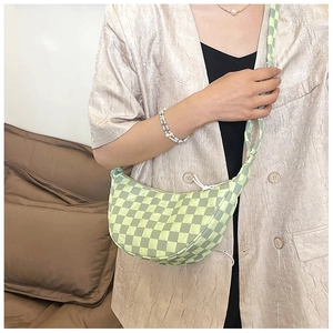 Dettaglio della borsa a mezzaluna a scacchi verde e gialla con tracolla larga alla moda