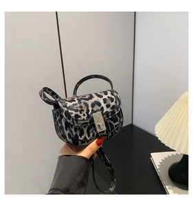 Close-up of leopard print handbag with silver metal buckle and adjustable shoulder strap
