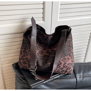 Detail of adjustable leather strap and silver metal buckle on leopard canvas tote bag
