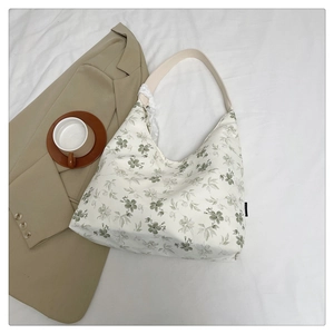 Détail d'un sac en toile florale avec poignée en cuir beige et bordure en dentelle