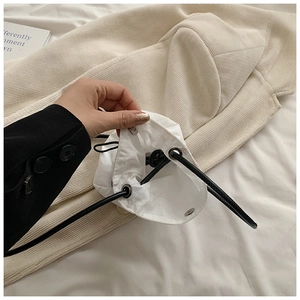 Detail of white mini nylon pouch showing drawstring closure and metal snap button