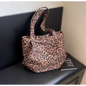 Detail of leopard print tote bag on a black bench highlighting canvas texture and pattern