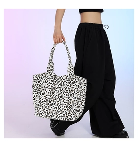 Action shot of the leopard print canvas tote bag carried by a model in casual pants