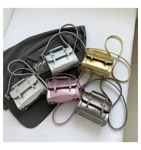 Detail of five mini metallic crossbody messenger bags with textured finish and buckles