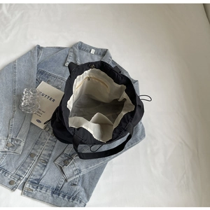 Detail view of the black tote bag interior showing zipper pocket and cream lining