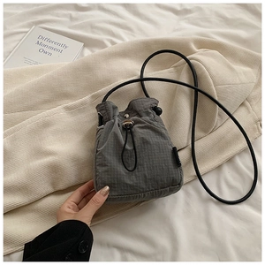 Detailed view of grey ripstop nylon drawstring bucket bag on minimalist fabric background