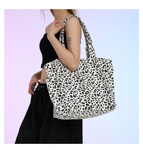Detailed side view of a large leopard print canvas tote bag with reinforced handles