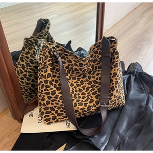 Detail of leopard print canvas tote bag featuring adjustable leather strap and metal buckle