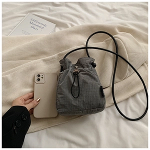 Close-up of drawstring nylon bucket bag with grey plaid texture and black shoulder strap
