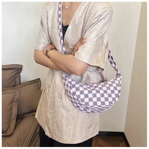 Dettaglio di una borsa a mezzaluna a scacchi rosa e grigi indossata a spalla