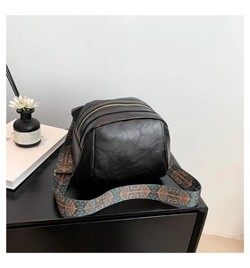 Detail einer schwarzen Umhängetasche mit Doppelreißverschluss und buntem Boho-Gurt
