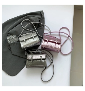 Three metallic mini crossbody bags in silver, pink, and grey on a grey blazer