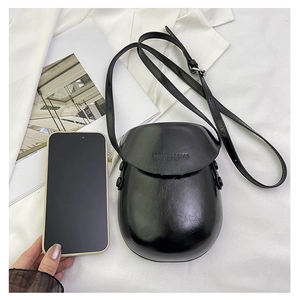 Mini black glossy saddle bag shown next to a smartphone for precise size comparison