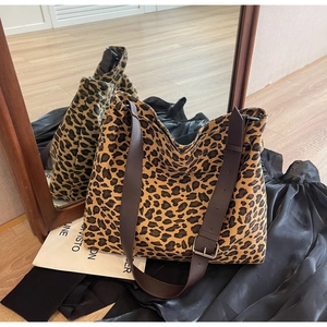 Detail of leopard print canvas tote with adjustable brown leather shoulder strap and buckle