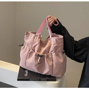 Detail of dusty pink nylon tote bag with drawstring pocket and ruched texture finish