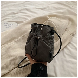 Detail of dark grey nylon drawstring bucket bag showing vertical texture and adjustable strap