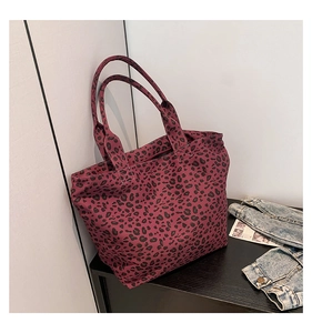 Close-up of leopard print canvas tote bag in burgundy and black with dual handle detail