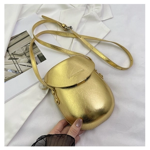 Close-up of golden metallic saddle bag with pleated leather texture on white fabric