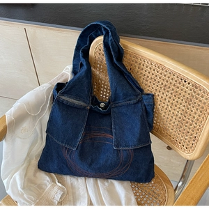 Detail of dark blue denim tote with orange embroidery and functional double front pockets