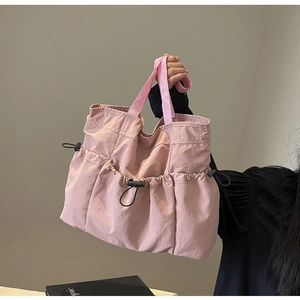 Close-up of pink pleated tote bag with functional drawstring pockets and fabric strap