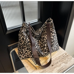 Close-up of leopard print canvas bag with brown textured faux leather strap and buckle