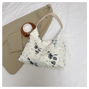 Détail d'un sac cabas floral avec anse en cuir et foulard en dentelle sur un blazer