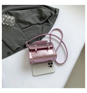 Top-down view of metallic pink square messenger bag with scale reference to a phone