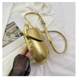 Detail shot of golden textured metallic leather crossbody bag with rounded saddle shape