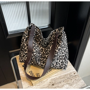 Detail shot of leopard print canvas tote bag with brown leather straps on marble surface