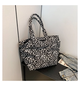 Detail of classic black and white leopard print tote bag on a dark wooden surface