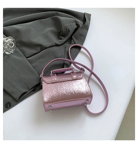 Close-up of metallic pink messenger bag with crinkle texture and silver bottom studs