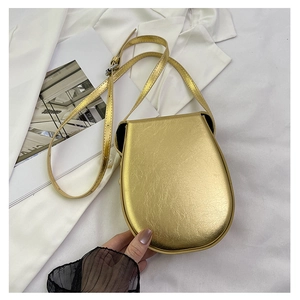 Detail of a metallic gold saddle bag with textured finish on a fashion magazine