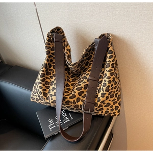 Detail of adjustable brown leather strap and buckle on leopard print canvas hobo bag