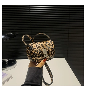Macro detail of leopard print saddle bag featuring metal buckle and leather texture