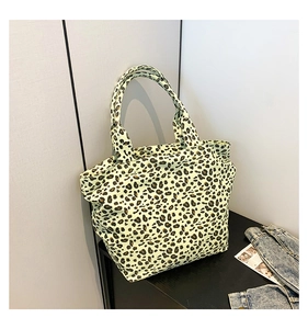 Close-up of leopard print tote bag placed on a wooden table with denim jacket and magazine