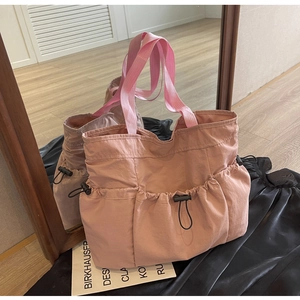 Pink pleated tote bag detail showing three drawstring front pockets and mirror reflection