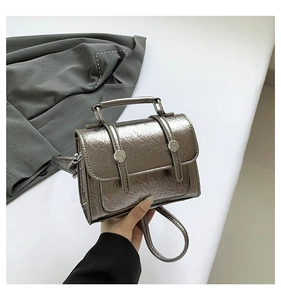 Detail showing metallic silver cracked texture leather and buckle on a mini messenger bag