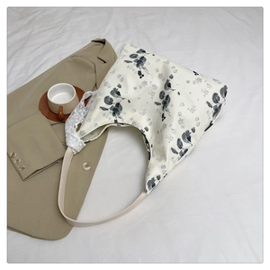 Détail du sac cabas floral en toile avec bandoulière en cuir crème et bordure en dentelle