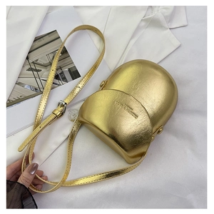 Close-up of golden metallic textured saddle bag with embossed fashion text and strap
